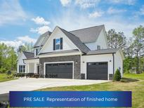 Charming two-story home with a three-car garage, stone accents, and manicured lawn under a sunny sky at 109 Hewitt Woods Dr, Clayton, NC 27527