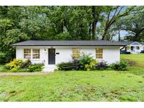Charming, one story, white brick home, with black front door and green landscaping at 117 Bertie Dr, Raleigh, NC 27610