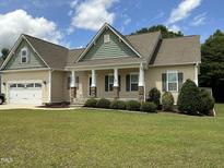 Charming single-story home showcasing a well-manicured lawn, neutral siding, and inviting front porch with stone accents at 119 Hunterwood Pl, Benson, NC 27504