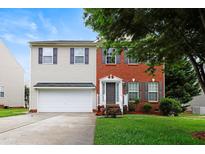Charming two-story home with a combination of brick and siding exterior, showcasing a well-maintained lawn and a two-car garage at 1405 Merrilow Ct, Wake Forest, NC 27587