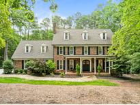 Classic brick home with manicured landscaping, dormer windows and covered front porch offers timeless curb appeal at 1501 Chatsworth Ln, Raleigh, NC 27614