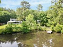 Secluded home featuring a pond and dock surrounded by mature trees creating a private, picturesque setting at 183 Birnamwood Dr, Chapel Hill, NC 27516
