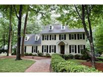 Stately two-story home featuring dormer windows, black shutters, manicured landscaping, and a brick pathway at 2216 Countrywood North Rd, Raleigh, NC 27615