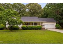 Charming ranch-style home featuring a welcoming front porch and lush, mature landscaping at 231 Harris Rd, Smithfield, NC 27577