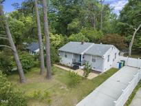 Charming home featuring a light gray exterior, a gray roof and a well-manicured lawn at 2409 Derby Dr, Raleigh, NC 27610