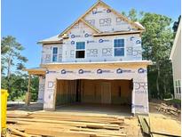 Unfinished two-story home exterior showcasing the frame with an attached two-car garage and lumber on the front lawn at 243 Steel Springs Ln # 25, Angier, NC 27501