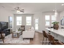 Bright living room with hardwood floors, a ceiling fan, and lots of natural light from multiple windows at 3916 Well Fleet Dr, Fuquay Varina, NC 27526