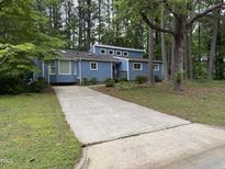 Charming blue house with a long driveway surrounded by lush trees at 507 Holtz Ln, Cary, NC 27511