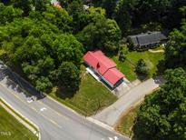 Aerial view of charming home with a red roof surrounded by lush greenery and a well-maintained lawn at 519 W Raleigh St, Siler City, NC 27344