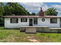 Charming white home featuring black shutters and a red metal roof, providing a modern touch to the classic design at 519 W Raleigh St, Siler City, NC 27344