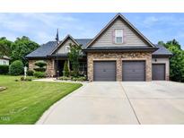 Charming home featuring a meticulously manicured lawn and a spacious three car garage at 67 Marshlane Way, Clayton, NC 27527