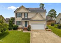 Charming two-story home featuring solar panels, a well-maintained lawn, and a two-car garage at 76 Haywood St, Spring Lake, NC 28390