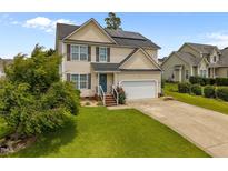 Charming two-story home featuring solar panels, a two-car garage, and a well-manicured front lawn at 76 Haywood St, Spring Lake, NC 28390