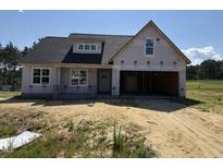 A new home's exterior with a two-car garage and covered porch, ready for customization and landscaping at 82 Laramie Ln, Selma, NC 27576