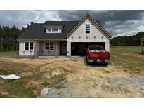 New home under construction, featuring a black roof, covered porch, and an attached two-car garage at 82 Laramie Ln, Selma, NC 27576