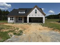 New construction exterior shows black roof, garage, and unfinished yard in a developing neighborhood at 82 Laramie Ln, Selma, NC 27576