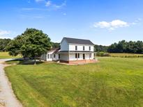 Charming two-story farmhouse with a covered front porch and expansive green lawn at 8365 Aaron Creek Church Rd, Oxford, NC 27565