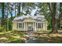 Charming yellow home with welcoming front porch and mature trees in a peaceful neighborhood at 940 Hill St, Rocky Mount, NC 27801