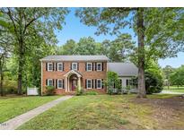 Charming two-story brick home with a manicured lawn and mature trees at 9509 Greenfield Dr, Raleigh, NC 27615