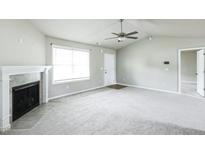 Bright living room features a fireplace, large window, and ceiling fan at 103 Hampshire Pl, Kenly, NC 27542