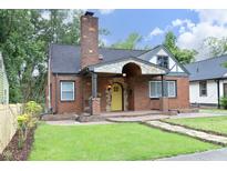 Charming brick home with a striking yellow front door and covered entryway with stone detailing at 106 E Club Blvd, Durham, NC 27704