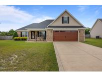 Charming brick home featuring an attached two-car garage and well-manicured front lawn at 106 Lockwood Dr, Cameron, NC 28326