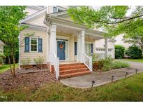 Charming front porch with brick steps, white railings, blue shutters, and a blue door with a wreath at 116 Hamilton Hedge Pl, Cary, NC 27519