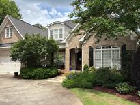 Charming brick home features a well-manicured lawn, mature trees, and a welcoming front porch at 1210 Brooks Ave, Raleigh, NC 27607