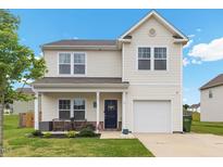 Charming two-story home featuring a welcoming front porch, attached garage, and well-maintained lawn at 13 Toplanders Ter, Gibsonville, NC 27249