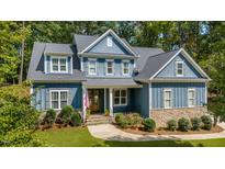 Charming two-story home with blue siding, stone accents, landscaped yard and American flag at 147 Gentry Dr, Pittsboro, NC 27312