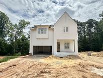 Two-story white home featuring an attached garage with unfinished yard space and wooded lot at 1701 Burnette Garden Path, Raleigh, NC 27612