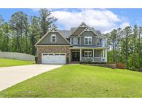 Charming two-story home featuring a stone facade, a two-car garage, and a welcoming front porch at 187 Farrah-Shea Way, Angier, NC 27501