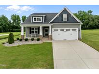Charming home featuring a two-car garage, well-manicured lawn, and inviting front porch at 206 Heart Pine Dr, Wendell, NC 27591