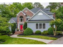 Charming two-story home boasts a brick facade and a vibrant red front door, enhanced by lush landscaping at 215 Collinson Dr, Chapel Hill, NC 27514