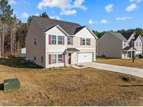 Two-story home with vinyl siding, a two-car garage, a driveway, and red shutters on the windows at 274 E Boulder Road Rd, Henderson, NC 27537