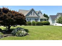 Charming home featuring a well-manicured lawn and vibrant landscaping including flowering plants and trimmed hedges at 479 Manchester Trail, Clayton, NC 27527