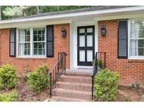 Charming brick home featuring a black front door with glass panes and black shutters on the windows at 4808 Berini Dr, Durham, NC 27705