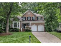 Traditional two-story brick home featuring a manicured lawn, attached two-car garage, and mature trees at 522 N Scotswood Blvd, Hillsborough, NC 27278