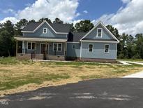 Charming two-story home featuring blue siding, a red front door and a welcoming front porch at 55 Leah Ln, Louisburg, NC 27549