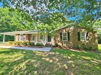 Charming brick home featuring a covered porch and lush green lawn at 5614 Skyline Dr, Durham, NC 27712