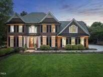 Stately brick home featuring manicured lawn, mature landscaping and elegant architectural details at 704 Walcott Way, Cary, NC 27519