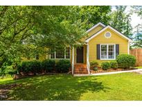 Charming yellow home with brick stairs, manicured shrubs and lush green lawn at 8116 Owenston Ct, Raleigh, NC 27612