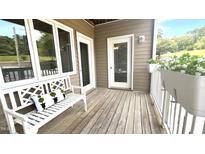 Inviting porch with white bench, decorative pillow, potted plants, and wooden floorboards at 923 Springfork Dr, Cary, NC 27513