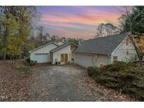 Inviting two-story home with a two-car garage and mature trees against a beautiful sunset at 103 Pony Express Cv, Louisburg, NC 27549