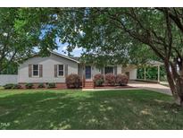 Charming single-story home with a well-maintained lawn, mature trees, and a convenient covered carport at 105 Poplar Dr. Dr, Clayton, NC 27520
