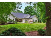 Charming brick home with a manicured lawn and lush landscaping in a serene, wooded setting at 1301 King Cross Ct, Raleigh, NC 27614