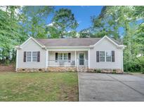 Charming single story home with a covered front porch, neutral siding, and manicured lawn at 144 Shawnee Dr, Louisburg, NC 27549