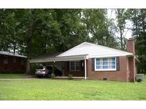 Charming brick home featuring a convenient carport, well-maintained lawn, and mature shade trees at 1809 S Garnett Ext, Henderson, NC 27536