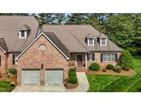 Charming brick home showcasing a two-car garage, dormer windows, and a well-manicured lawn at 2014 Muirfield Ct, Elon, NC 27244