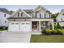 Charming two-story home featuring a covered front porch, a two-car garage, and manicured landscaping at 2083 Amalfi Pl, Apex, NC 27502